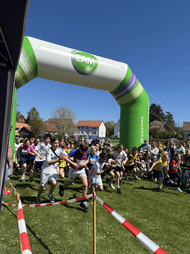 Start des Schülerlaufs: Kinder laufen unter dem Bogen los